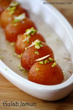 some food is in a white bowl on a wooden table and has pistachio sprinkles