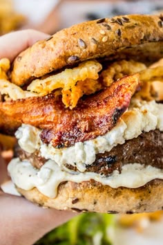 a close up of a person holding a hamburger with meat and cheese on it in their hand