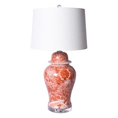 an orange and white lamp sitting on top of a table next to a white lampshade