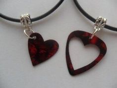 two red heart shaped pendants hanging from a black cord