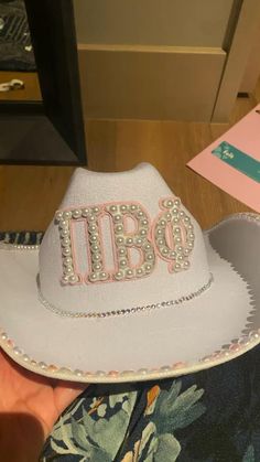 a person wearing a white cowboy hat with the word opi on it and pearls