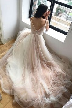 a woman is looking out the window in her wedding dress, wearing a long flowing gown