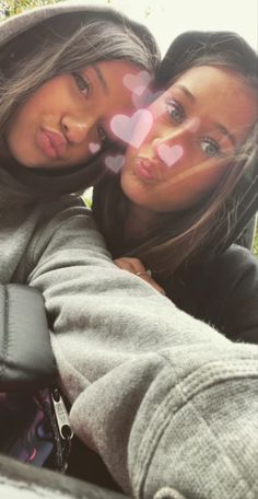 two women are taking a selfie in the back seat of a car with hearts drawn on it