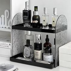 a black and white shelf with several bottles on it next to a cell phone, laptop and other personal care items