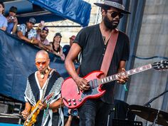 two men are playing guitars on stage while people watch