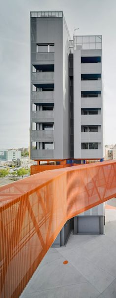 two tall buildings next to each other on top of a building with an orange walkway