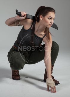 a woman kneeling down with a knife in her hand and holding it up to the side