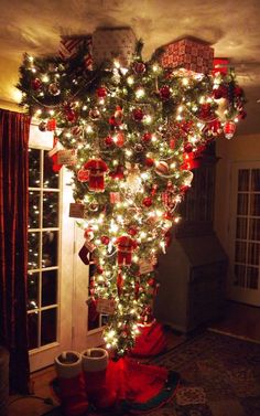 the christmas tree is decorated with red and white ornaments, lights, and stockings on it