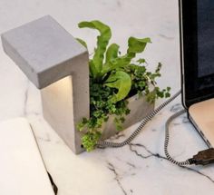 an open laptop computer sitting on top of a white marble table next to a planter