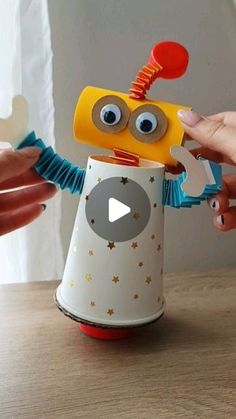 a person is holding a toy in front of a cup that looks like a robot