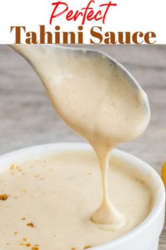 a spoon full of cream sauce being poured into a white bowl with an orange in the background