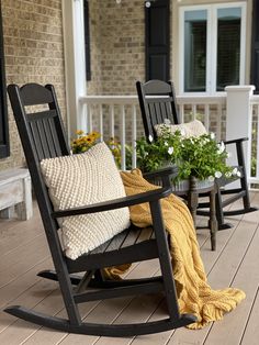 two rocking chairs on the front porch with pillows and flowers in vases next to them