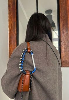 the back of a woman's jacket with beads and chains attached to her shoulder