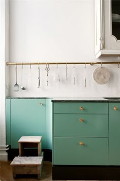 a green cabinet and stool in a room with white walls, wood floors and wooden flooring