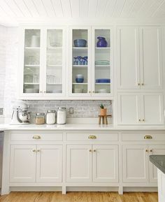 a kitchen with white cabinets and wooden floors