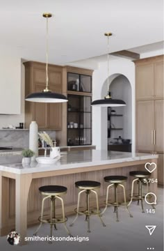 a kitchen with four stools in front of the island and three lights hanging from the ceiling