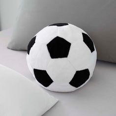 a black and white soccer ball sitting on top of a bed next to two pillows