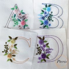 four embroidered napkins with flowers and the letter b, c, d, and e on them