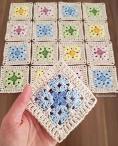 someone is holding up a crocheted square with small flowers on it and the squares are