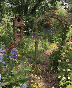 a garden with flowers and a bird house