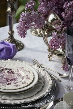 the table is set with purple flowers and silverware