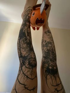 a person with tattoos holding up an orange stuffed animal in their arms and legs,