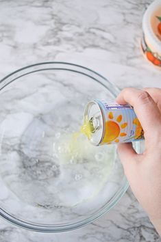 someone pouring orange juice into a glass bowl