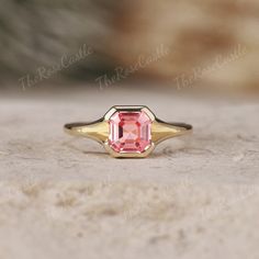 a pink tourmaline ring sitting on top of a stone surface with the words