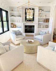 a living room filled with white furniture and a chandelier hanging from the ceiling