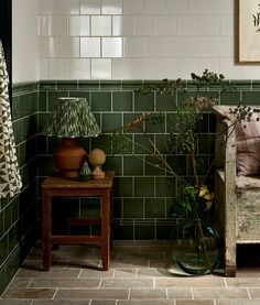 a room with green tiles and vases on the floor next to a wooden table