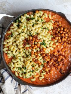 a pot filled with pasta and sauce on top of a table next to a towel