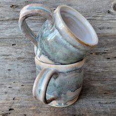 two coffee mugs stacked on top of each other in front of a wooden table