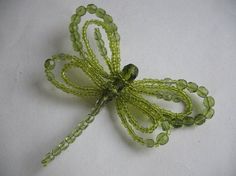 a green beaded dragon brooch sitting on top of a white table