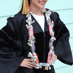 a woman wearing a graduation gown and holding a cell phone in her hand while standing next to a blue wall