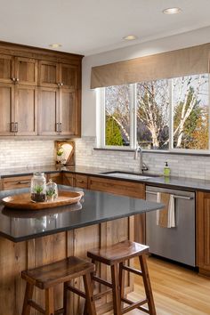 a kitchen with wooden cabinets and black counter tops, two stools at the island