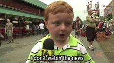 a young boy with red hair wearing a green and white shirt talking into a microphone