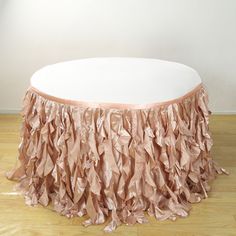 a round table topped with a pink ruffled cloth covered coffee tablecloth on top of a hard wood floor