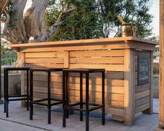 an outdoor bar with three stools next to it