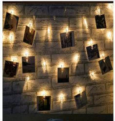 some lights are hanging on a brick wall with pictures and candles around them in the shape of hearts