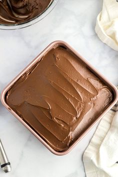 a pan filled with chocolate frosting on top of a counter