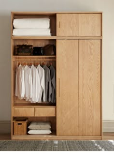 an open wooden wardrobe with clothes hanging on it