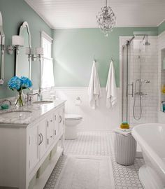 a bathroom with two sinks, a bathtub and a chandelier hanging from the ceiling