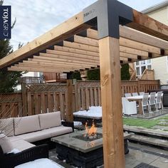 a fire pit in the middle of a patio with seating and an attached pergolan