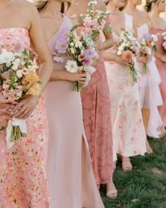 a group of women standing next to each other holding bouquets in their hands and wearing dresses with flowers on them