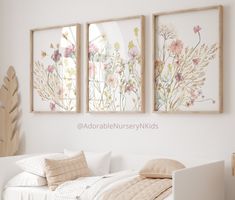 three framed pictures hang above a bed in a room with white walls and flooring