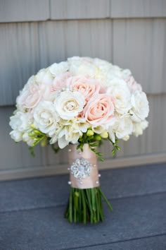 a bouquet of white and pink flowers is in a vase on the ground next to a wall