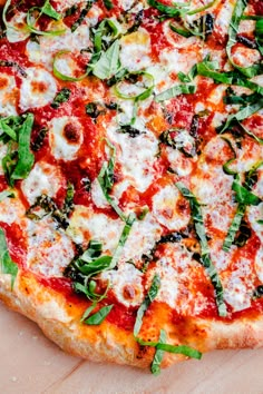 a pizza with cheese, spinach and other toppings sitting on a cutting board