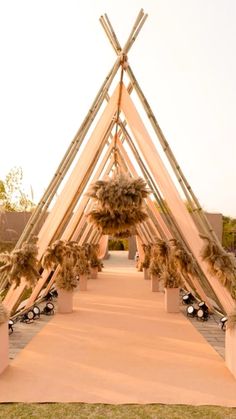 an outdoor wedding ceremony setup with bamboo poles and flowers on the aisle leading up to the entrance