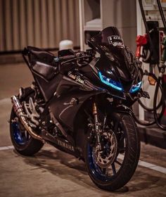 a black motorcycle parked in front of a gas station with blue lights on it's side