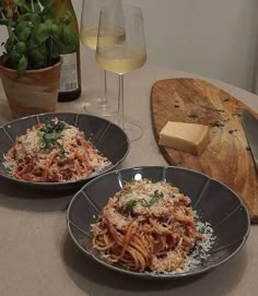 two plates of spaghetti with parmesan cheese and wine